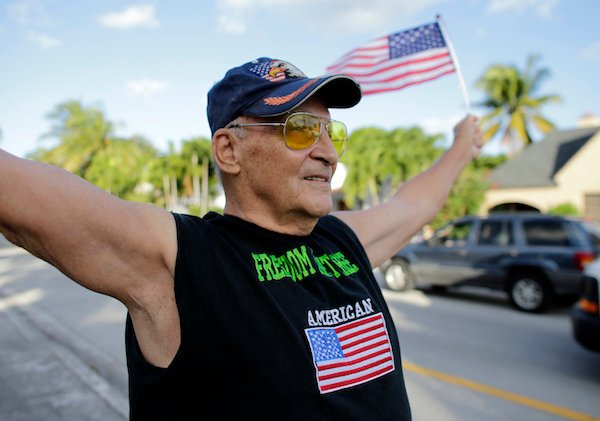 Peter Knapp, a supporter of Republican candidate Donald Trump, waves American flags as he stands outside his home on election day, Tuesday, Nov. 8, 2016, in Miami. (AP Photo/Lynne Sladky)